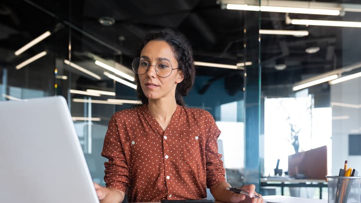 A woman working on a laptop in an office.