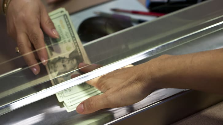 A person is putting money into a cash register.