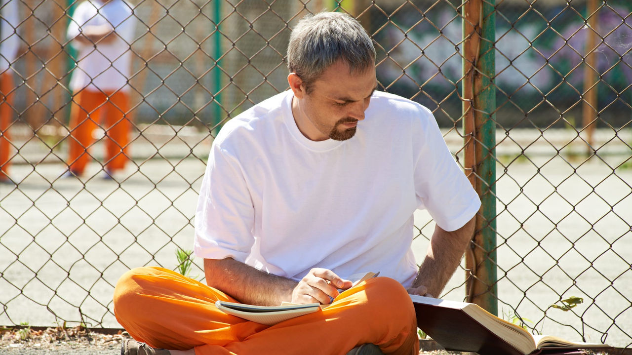 A man sitting on the ground reading a book.