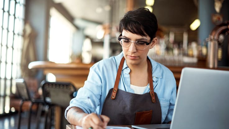 A woman working on a laptop in a cafe.