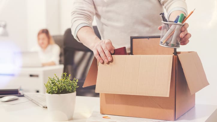 A man is opening a cardboard box in an office.