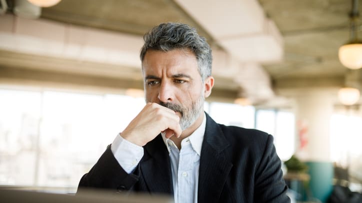 A man in a suit is looking at his laptop.