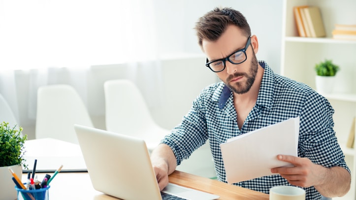 A man sitting at a desk with a laptop and papers.