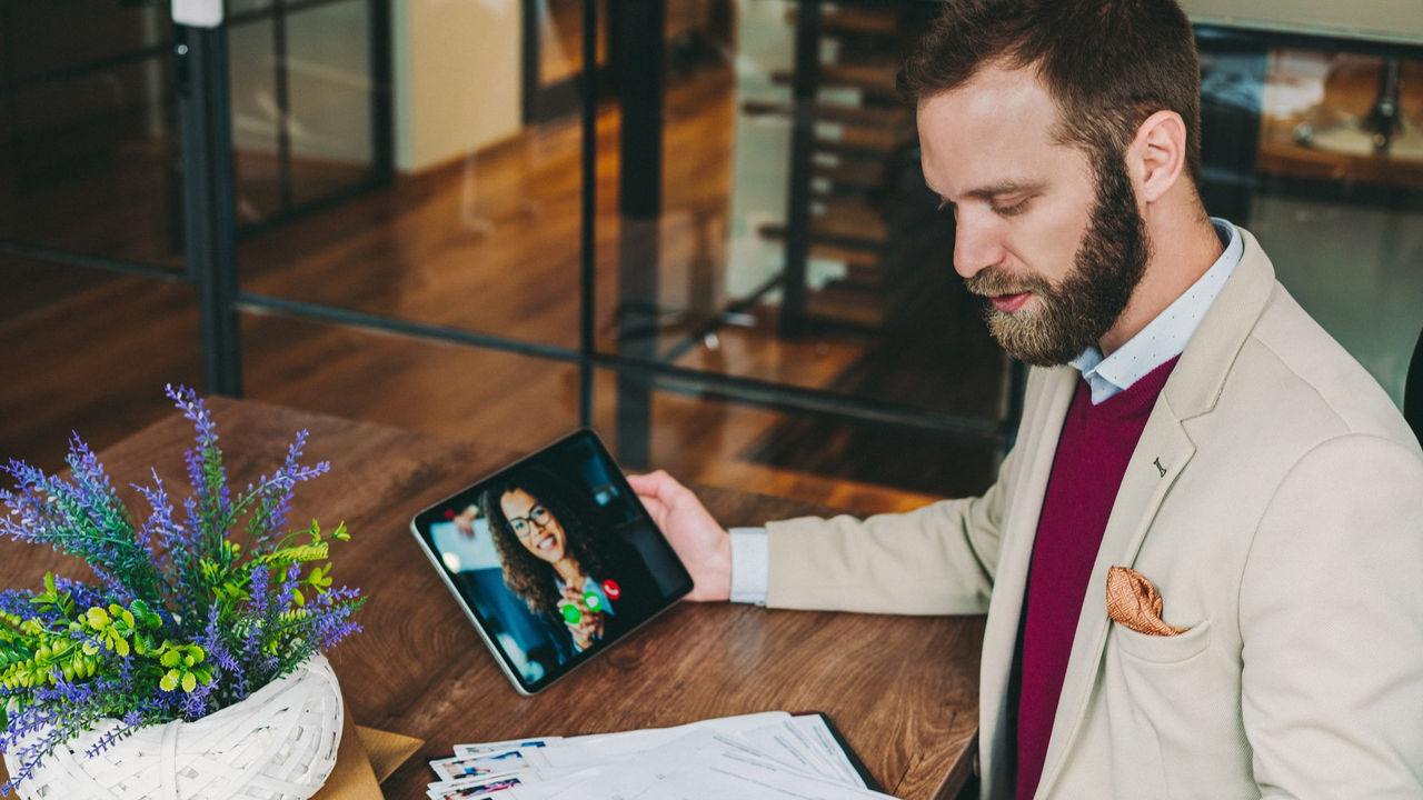 A man is sitting at a table with a laptop and a tablet.