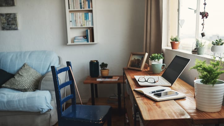 A desk with a laptop and a chair in front of a window.