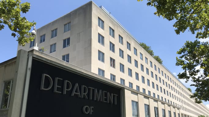 The department of state sign is in front of a building.