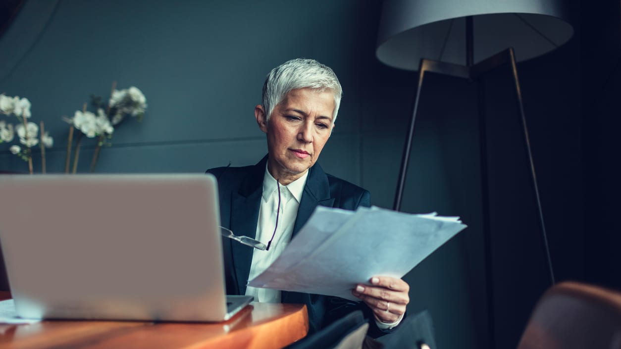 A woman sitting at a table looking at a laptop.