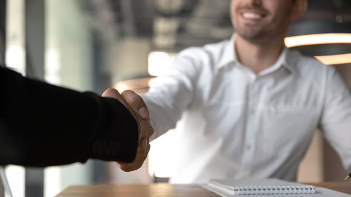 Two businessmen shaking hands at a desk.