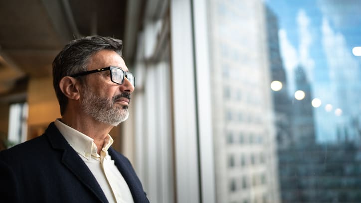 A businessman looking out of a window in an office.