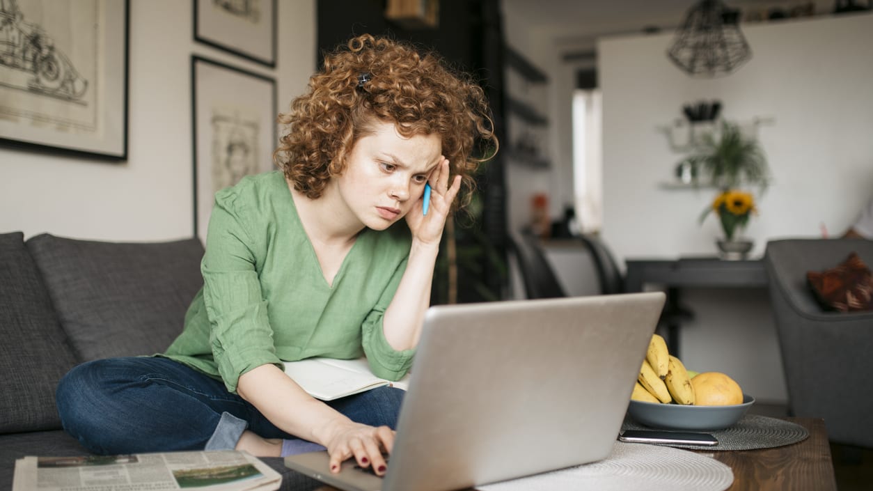 A woman sitting on a couch with a laptop on her lap.