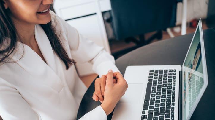 A woman sitting at a table with a laptop and a cup of coffee.