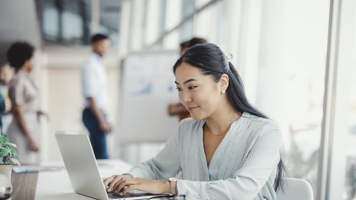 A woman is working on a laptop in an office.