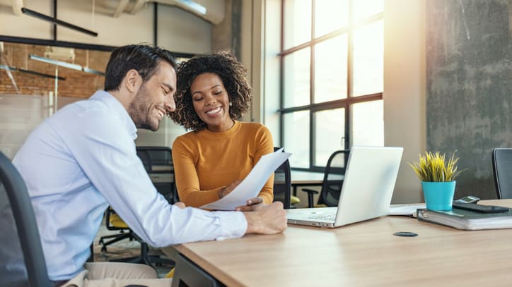 Two business people looking at a laptop in an office.