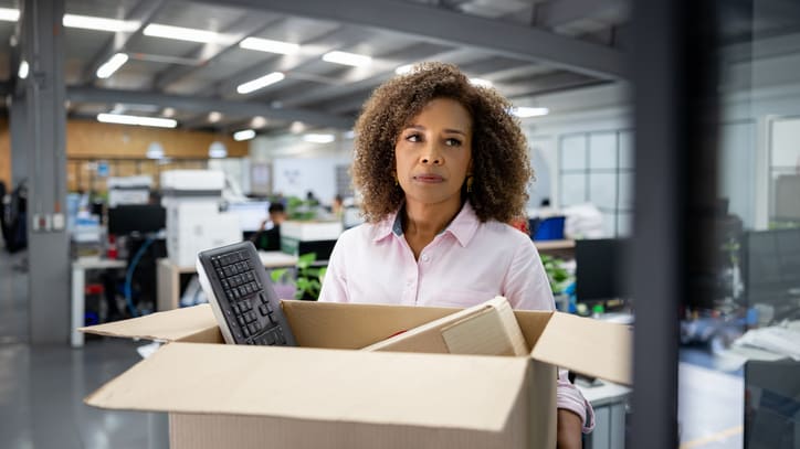 A woman holding a cardboard box in an office.