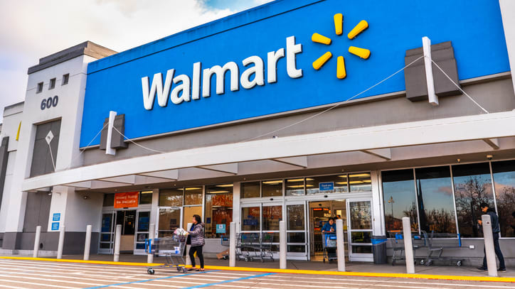 A picture of a walmart store with people walking in front of it.