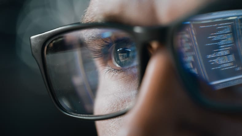 A man wearing glasses is looking at a computer screen.