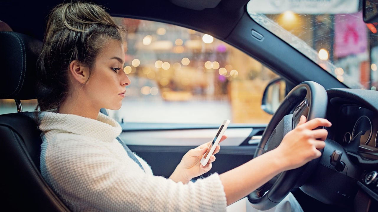 A woman driving a car while using her cell phone.