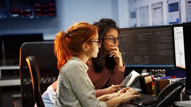 Two women working on computers in an office.