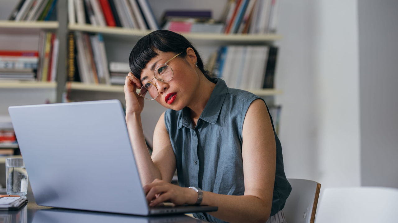 A woman sitting at a desk looking at her laptop.