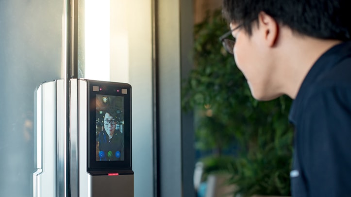 A man is looking at a camera on a door.