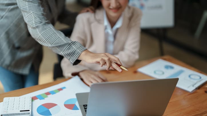 Two business people pointing at a laptop.