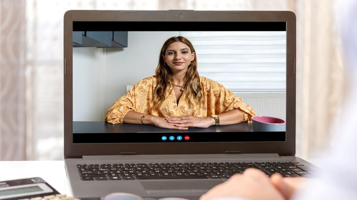 A woman is watching a video on a laptop screen.