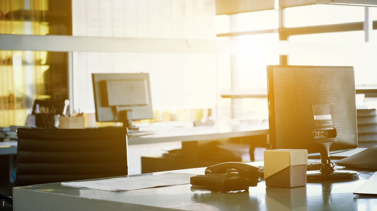 A desk with a computer and a telephone on it.