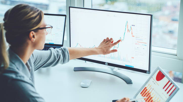 A woman is pointing at a graph on a computer screen.