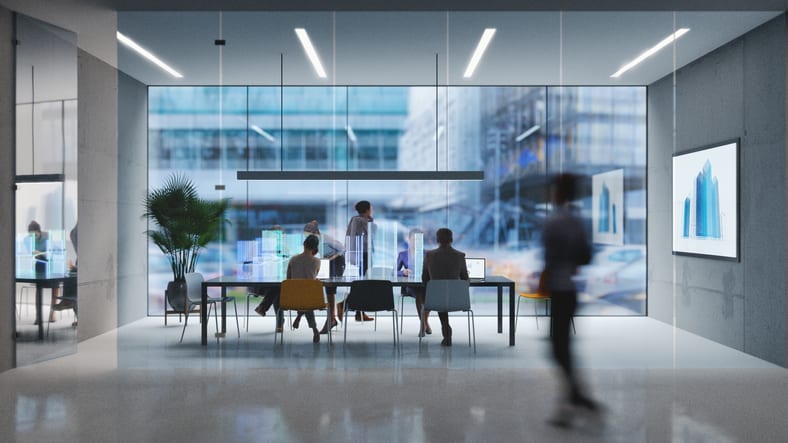 A meeting room with people sitting around a table.