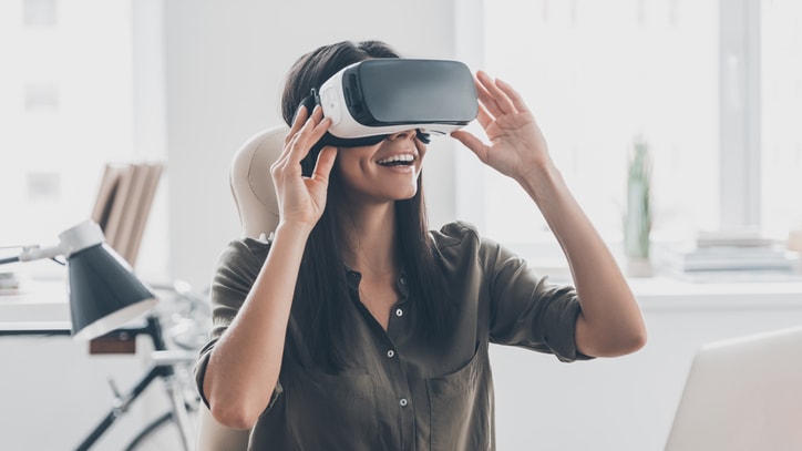 A woman wearing a virtual reality headset in front of a laptop.