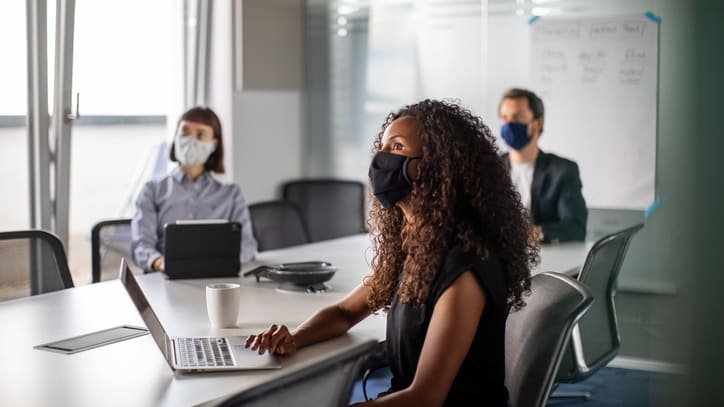 A woman wearing a face mask in a conference room.