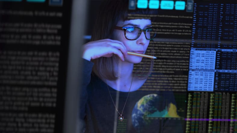 A woman in glasses is looking at a computer screen.