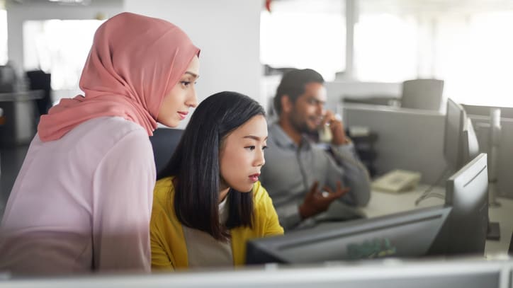 Two muslim women working at a computer in an office.