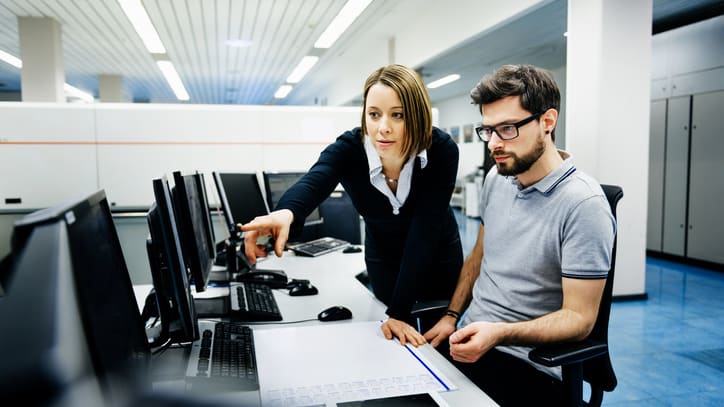 Two people working on computers in an office.