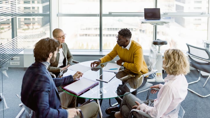 A group of business people sitting around a table in an office.