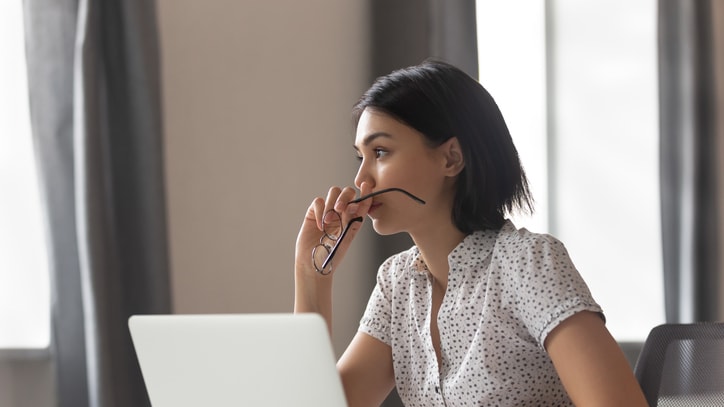 A woman is sitting at a desk with a laptop in front of her.