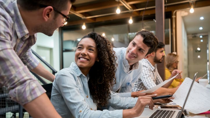 A group of people working on a laptop in an office.