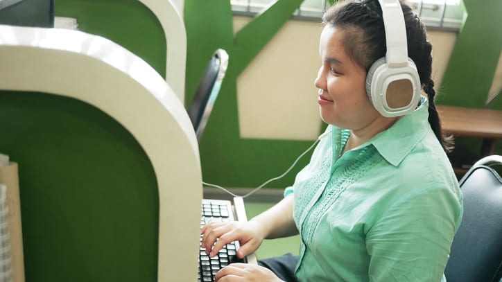 A woman wearing headphones is working on a computer.