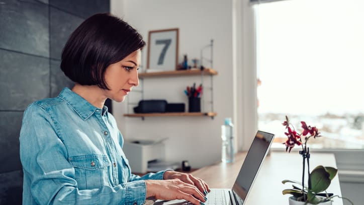 A woman working on a laptop in her home office.