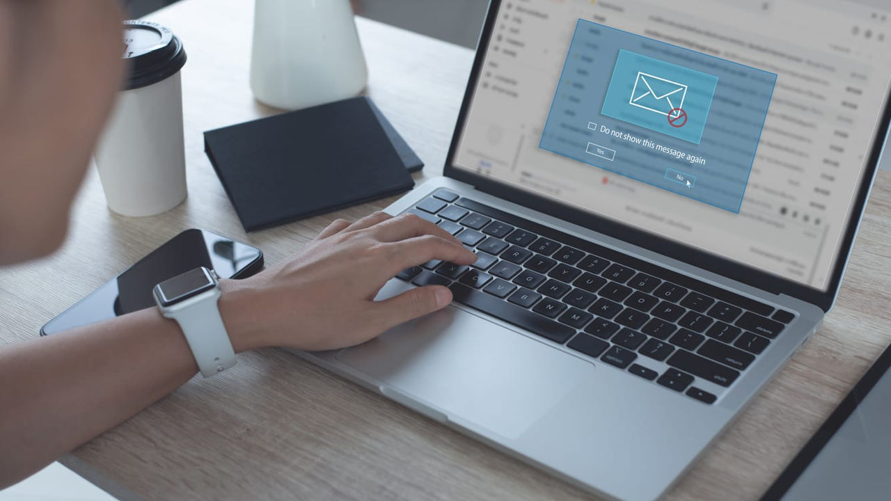 A man is using a laptop with an email icon on it.