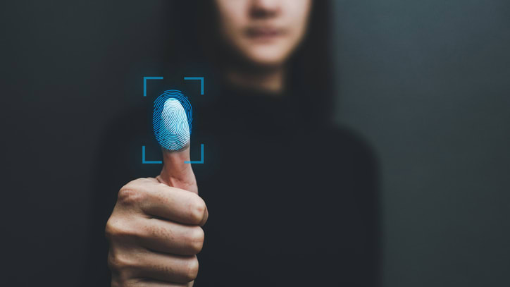 A woman is pointing her finger at a fingerprint sensor on a black background.