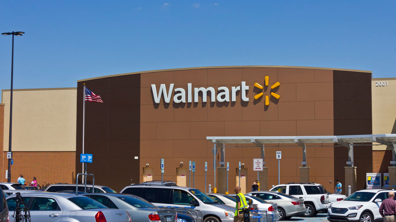 A walmart store with cars parked in front of it.