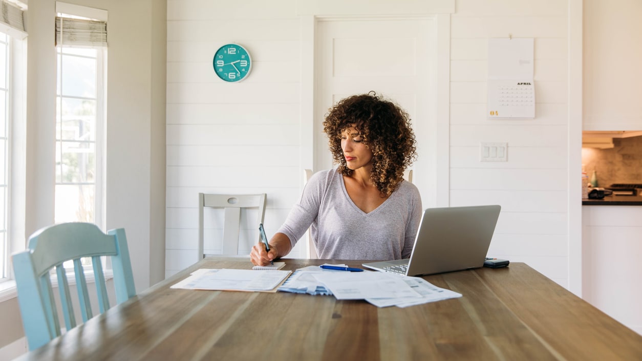 A woman sitting at a table with a laptop and papers.