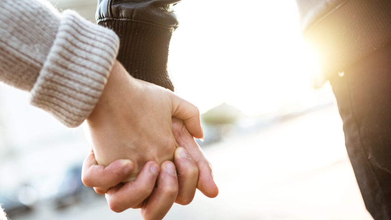 A man and woman holding hands in the street.