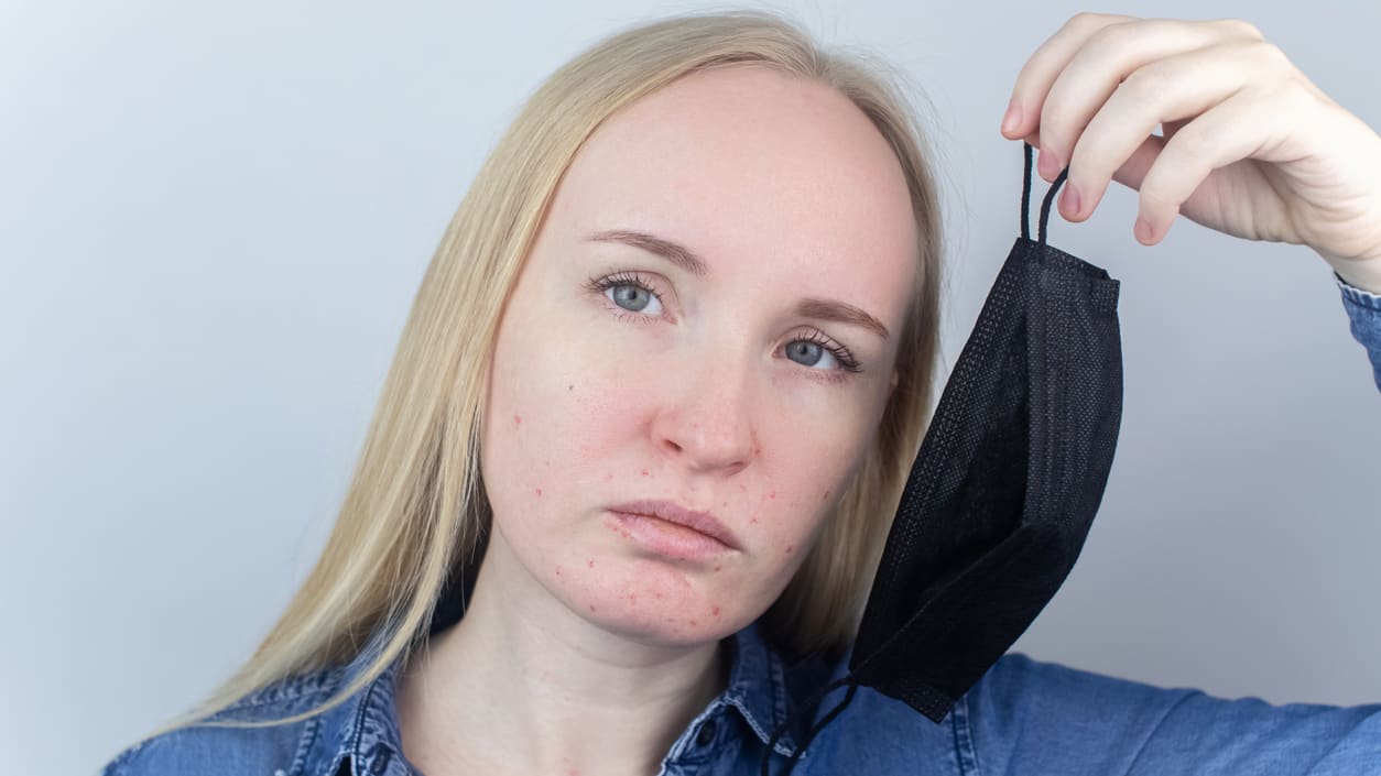 A woman is holding a black mask over her face.