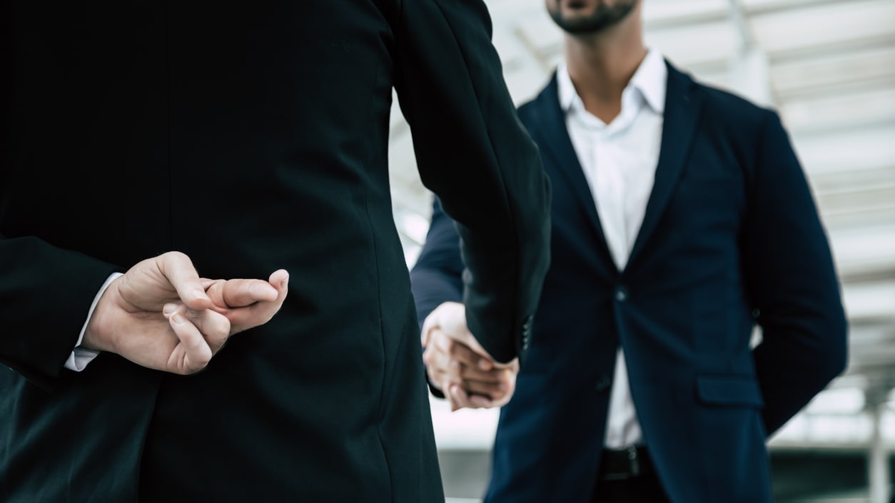 Two businessmen shaking hands in front of a building.