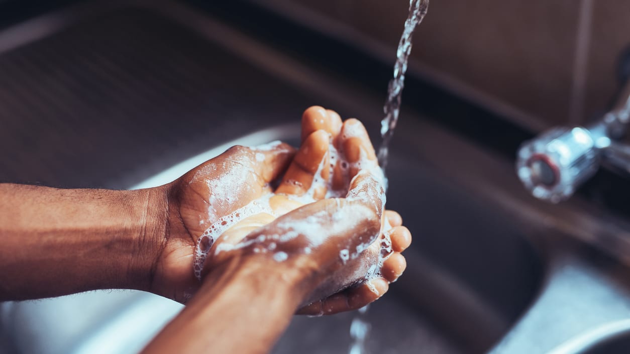 A person washing their hands in a kitchen sink.