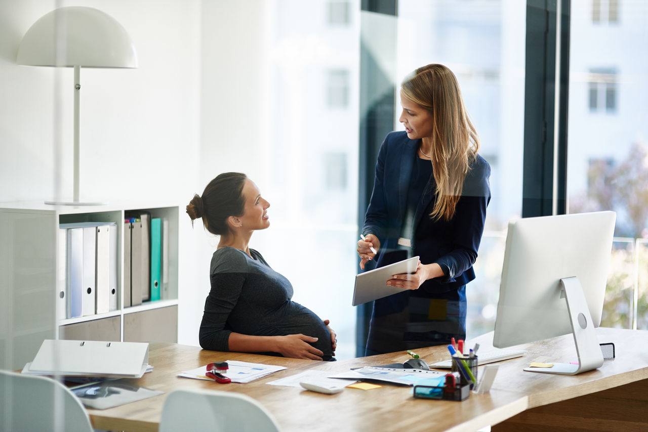 Shot of a pregnant businesswoman and a colleague using a digital tablet together in an office