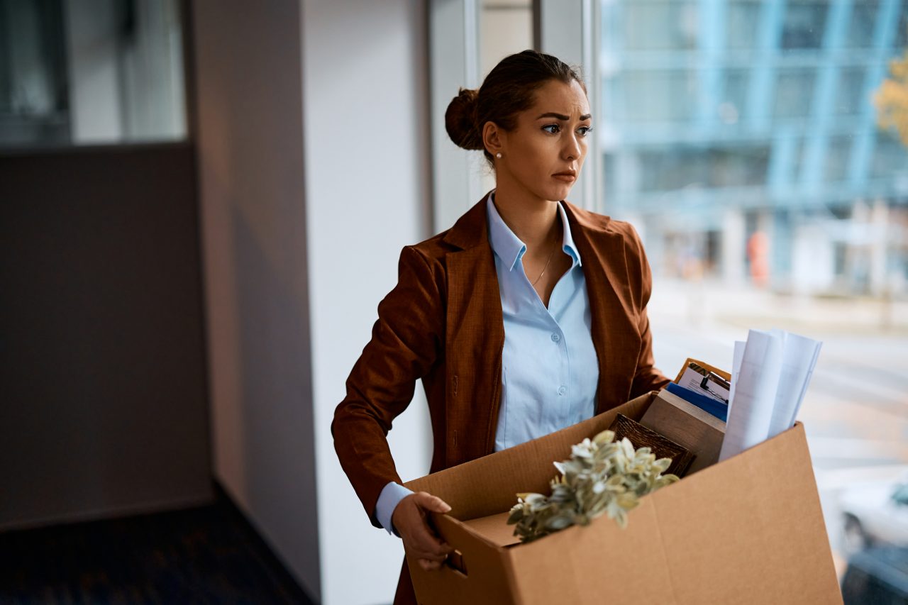 A woman leaves her place of business with her belongings after losing her job.