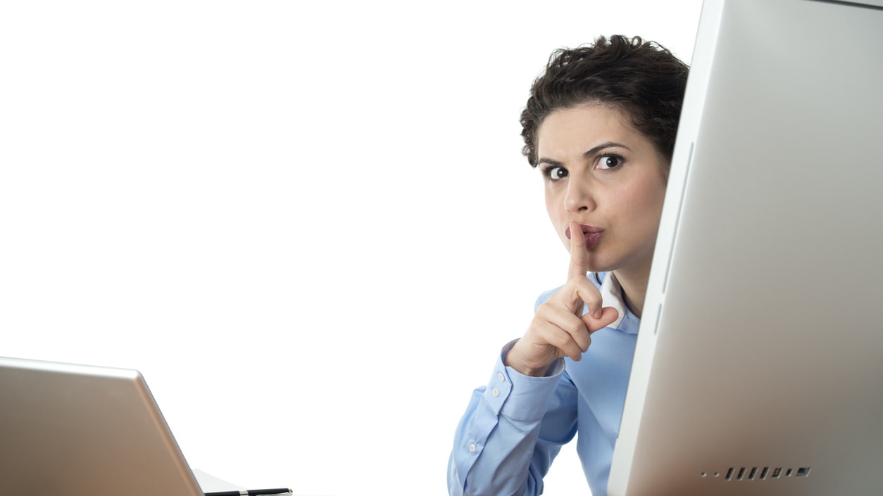 A woman looking at a computer screen with her finger in her mouth.